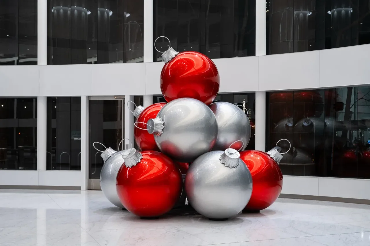 Oversized red and silver ornaments stacked on a polished floor beside lobby windows