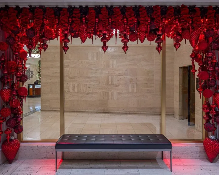 Red hanging ornaments framing a glass lobby entry behind a black upholstered bench