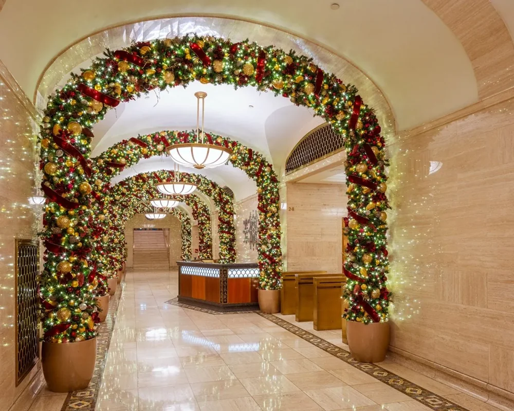 Garland wrapped around a series of arched openings in a stone lobby corridor
