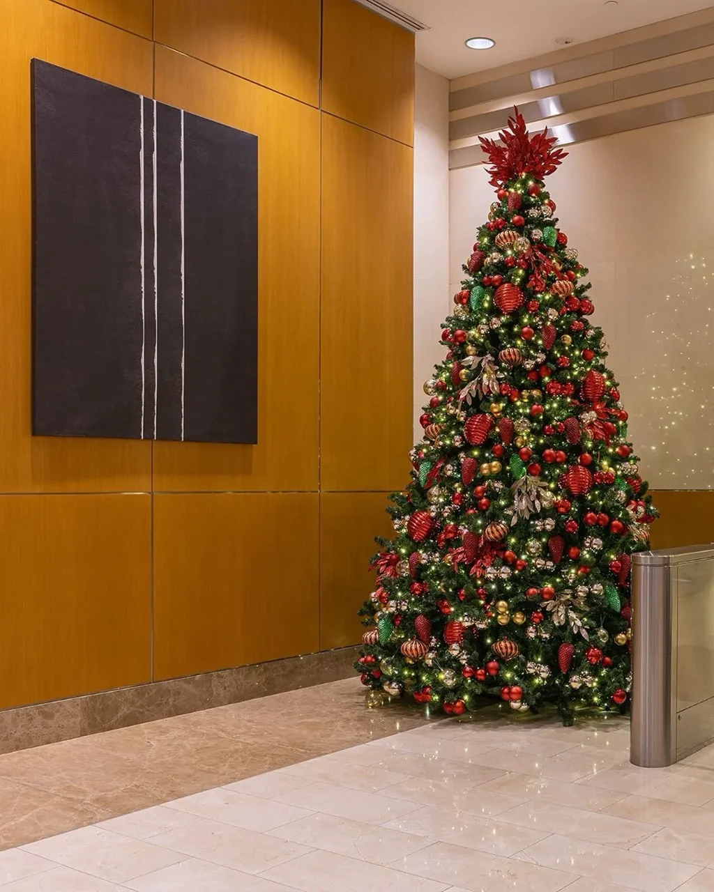 A tree with red and gold ornaments beside wood-paneled lobby walls