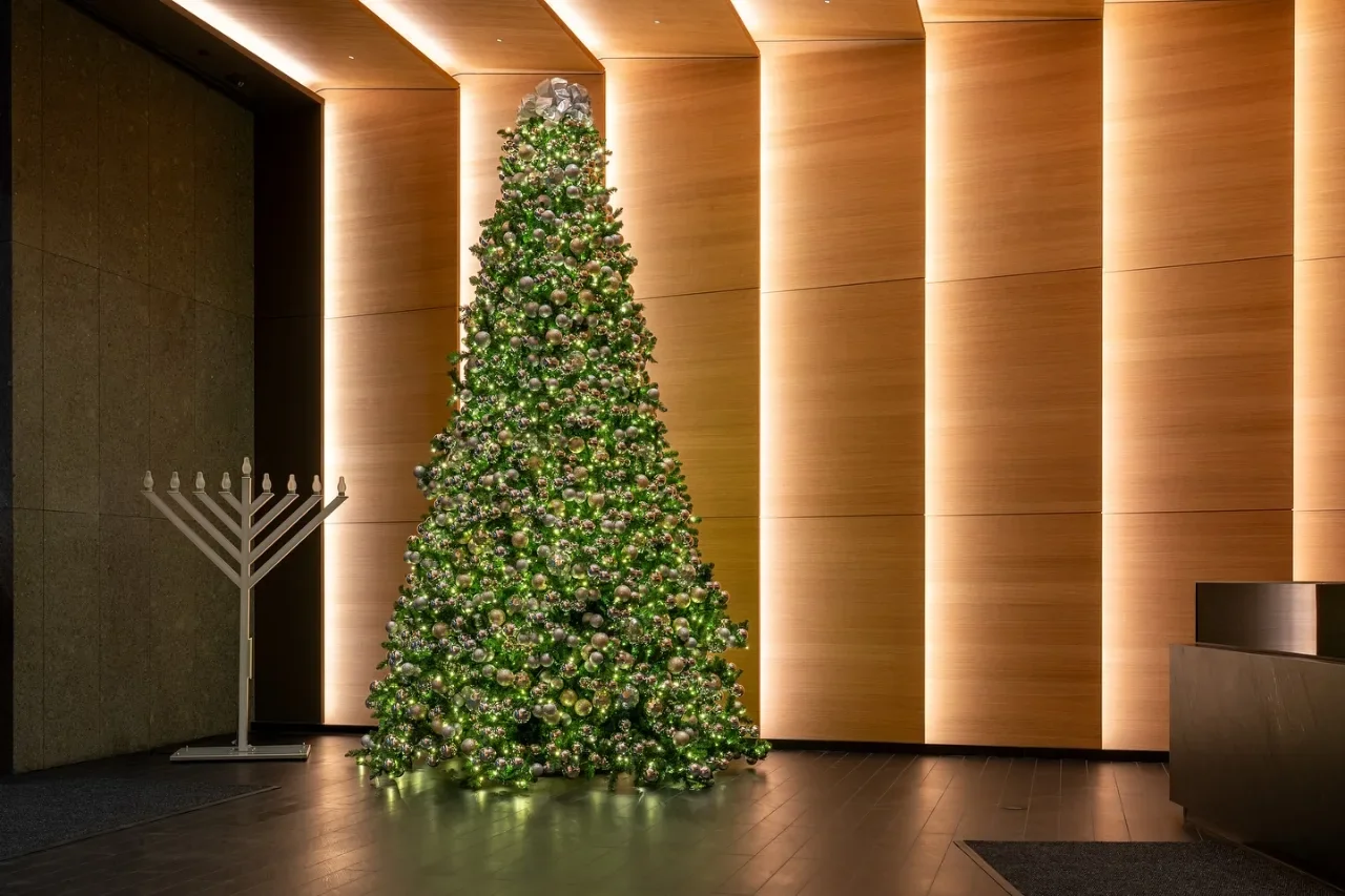 An illuminated tree and freestanding menorah beside wood-paneled lobby walls
