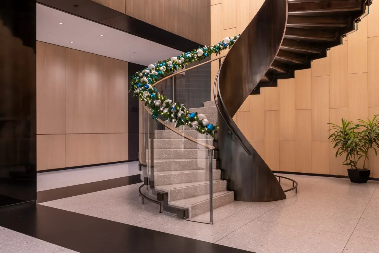 Garland with blue and silver ornaments along a curved staircase in a wood-paneled lobby